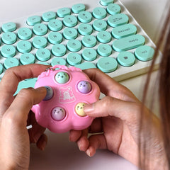 Pink hamster game fidget toy in hands with keyboard in background